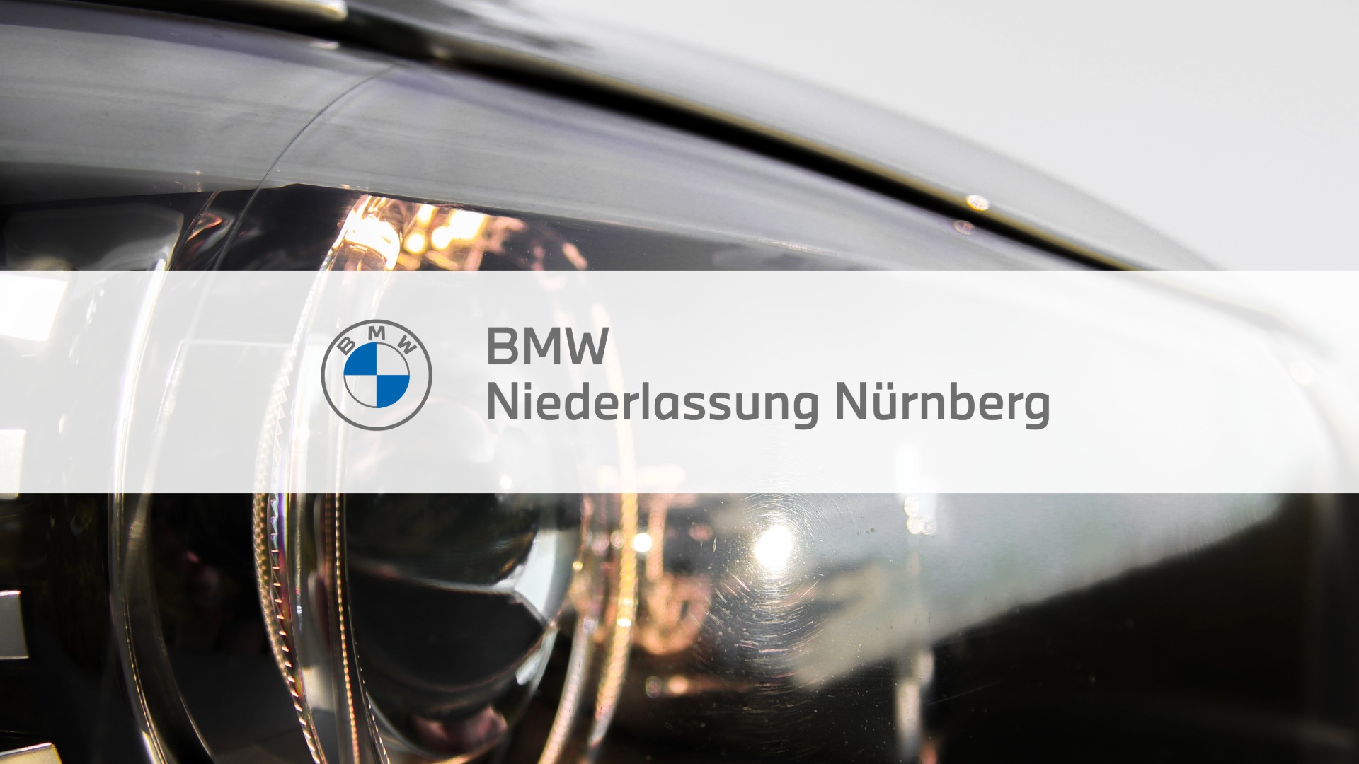 Logo der BMW-Niederlassung Nürnberg vor einem Auto-Scheinwerfer